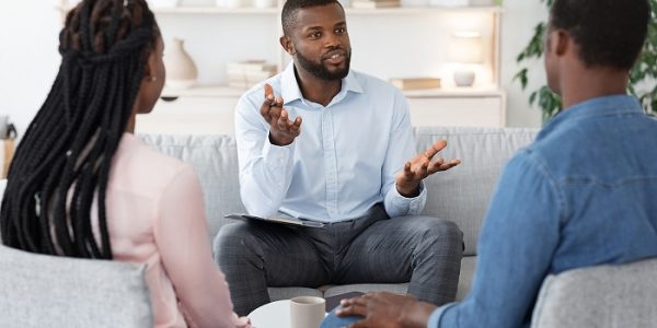 Family Psychotherapy. African American Couple Listening To Counselors Advices During Therapy Session In Office, Black Spouses Having Marital Counseling Meeting With Therapist, Selective Focus